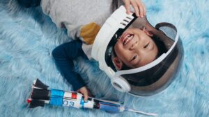 A cheerful child in astronaut costume pretends space adventures on a soft carpet.