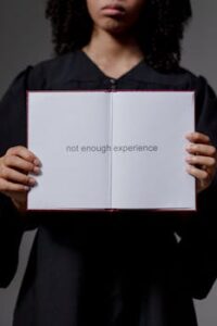 A graduate in a cap and gown holding a diploma with the text 'not enough experience'.