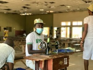 A young man sewing during the National Youth Service Corps program in Nigeria, promoting skill development.