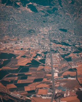 Aerial view showcasing a blend of urban sprawl and farmlands. Clear division of city and agriculture.