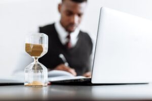 Businessman at desk with hourglass indicating time management and daily work routine.