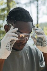 Close-up of a young worker adjusting safety glasses in outdoor setting.