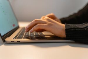 Close-up view of hands typing on a laptop keyboard, illustrating the concept of remote work and technology.