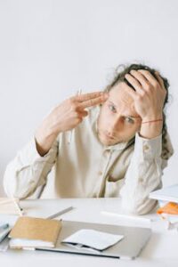 A young adult in an office feeling stressed and overwhelmed by workload.