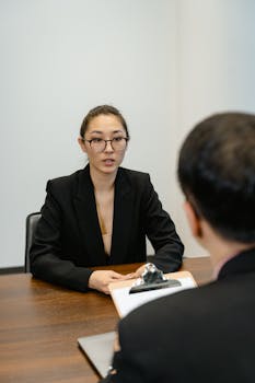 Asian woman interview with eyeglasses, business attire and formal setting.