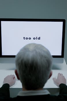 Senior man facing his computer screen displaying age-related message, highlighting ageism in technology.